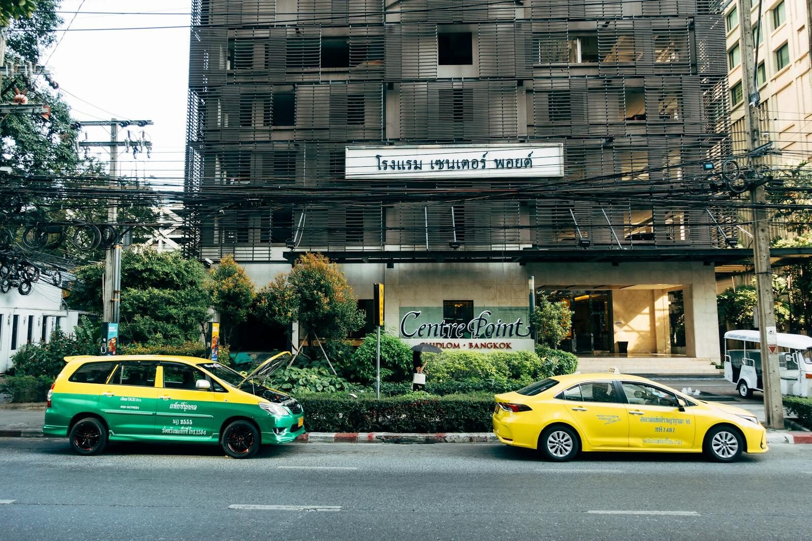 Colorful taxis parked outside Centre Point Hotel in Bangkok, showcasing urban transportation.