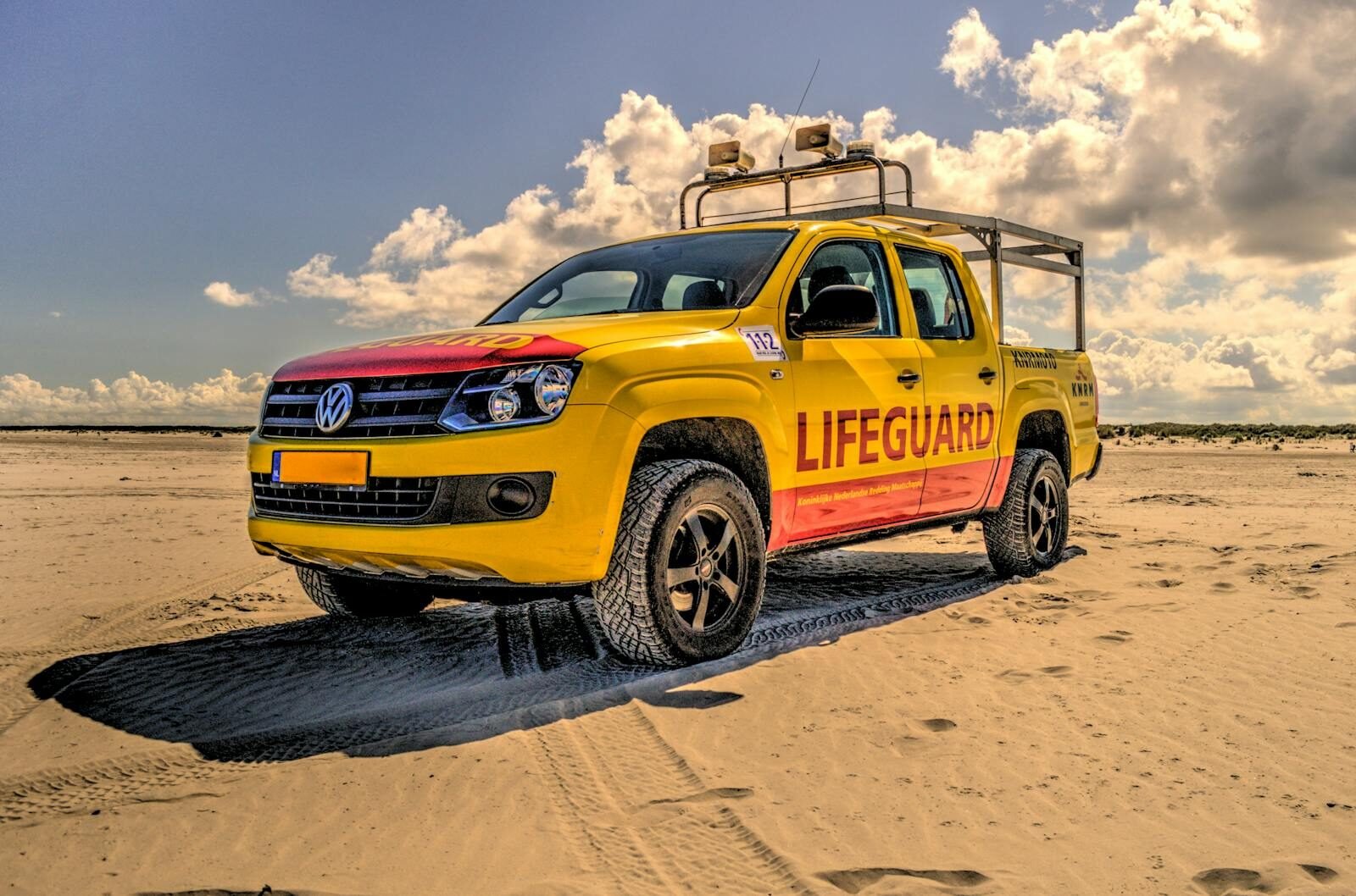 A vibrant yellow lifeguard vehicle parked on a sunny beach, ensuring safety for beachgoers.